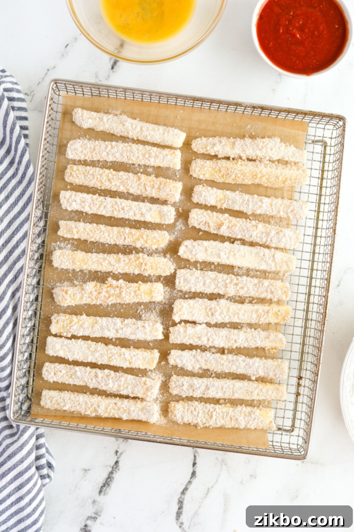 Breaded halloumi sticks arranged in a single layer on an air fryer tray, ready for cooking.