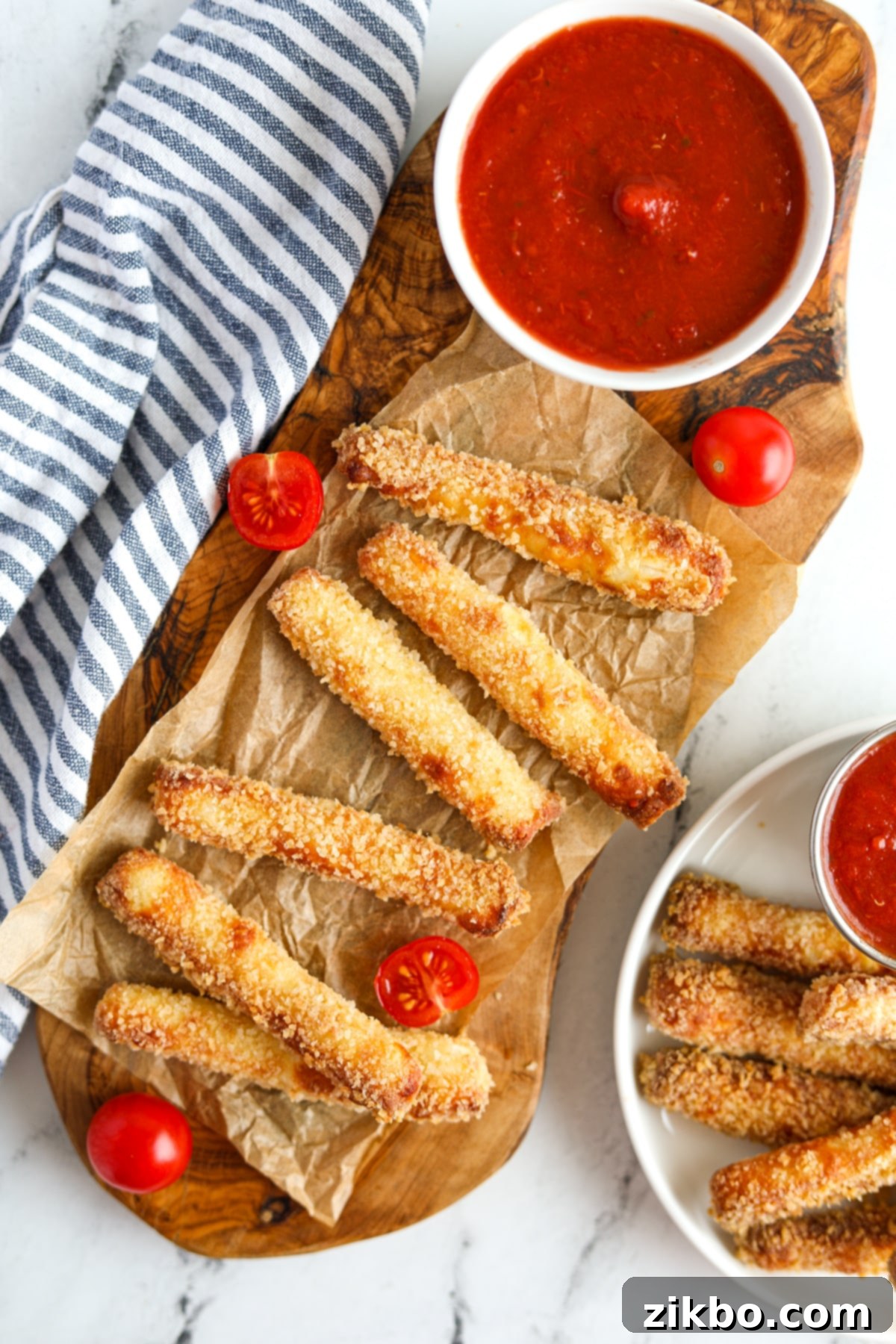A wooden platter filled with golden brown, crispy halloumi fries and a small bowl of pizza sauce for dipping.