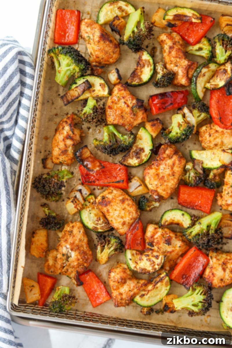 An air fryer tray filled with cooked vegetables and chicken.