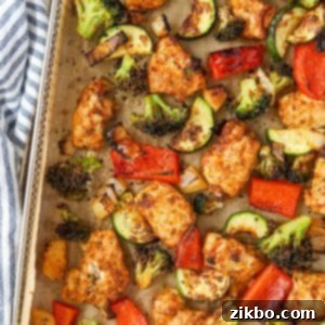 An air fryer tray filled with chicken pieces and vegetables.