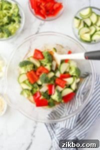 A bowl with broccoli, peppers, onions, and zucchini added to it.