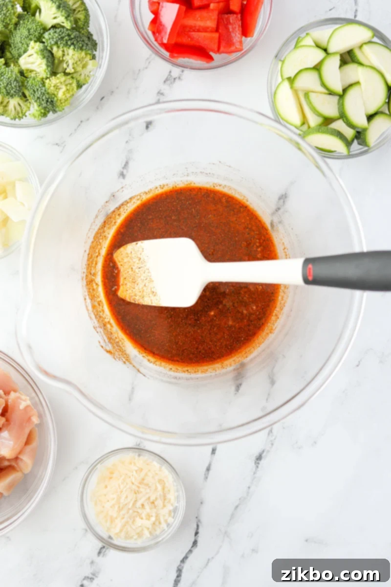 A bowl with a silicone spatula stirring seasonings and oil together.