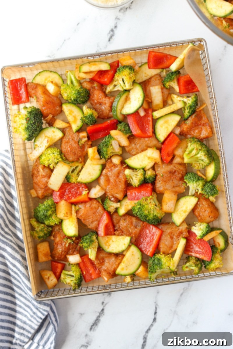 An air fryer tray filled with chicken and vegetables.