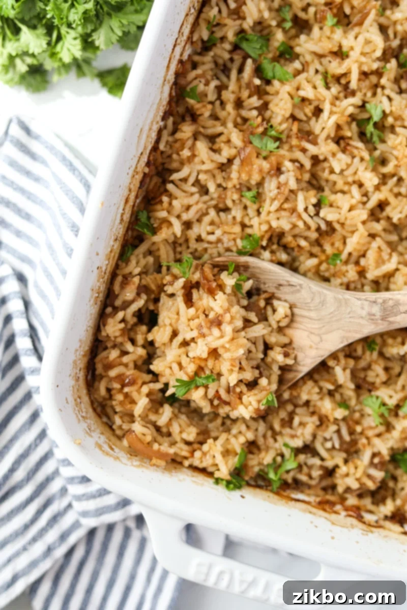 Golden Butter Rice 11 A baking dish filled with fluffy rice, with a wooden spoon scooping a portion.