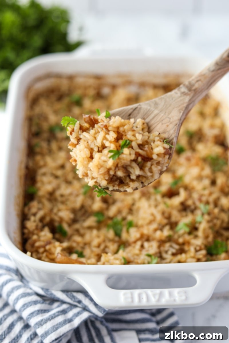 Golden Butter Rice 12 A wooden spoon scooping some rice from a baking dish.
