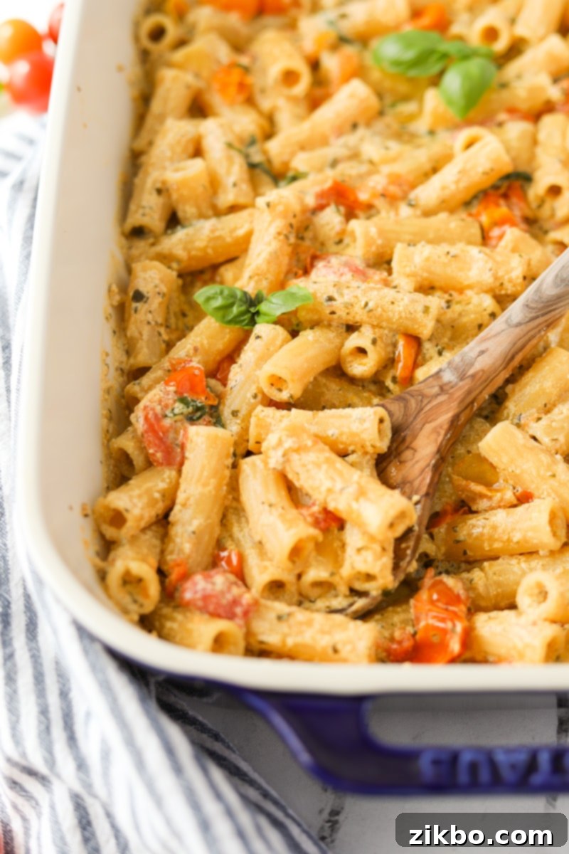 A spoon scooping up a portion of creamy Boursin pasta, highlighting the melted cheese and tender tomatoes within the sauce.