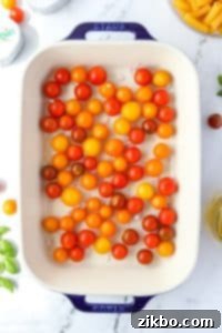 A baking dish filled with cherry tomatoes, ready for oil.