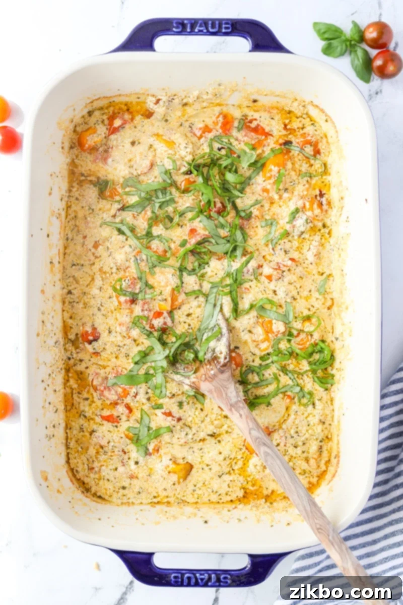 Close-up of the baking dish with the roasted tomatoes and melted Boursin, now mixed into a creamy, chunky sauce, with fresh basil stirred in.