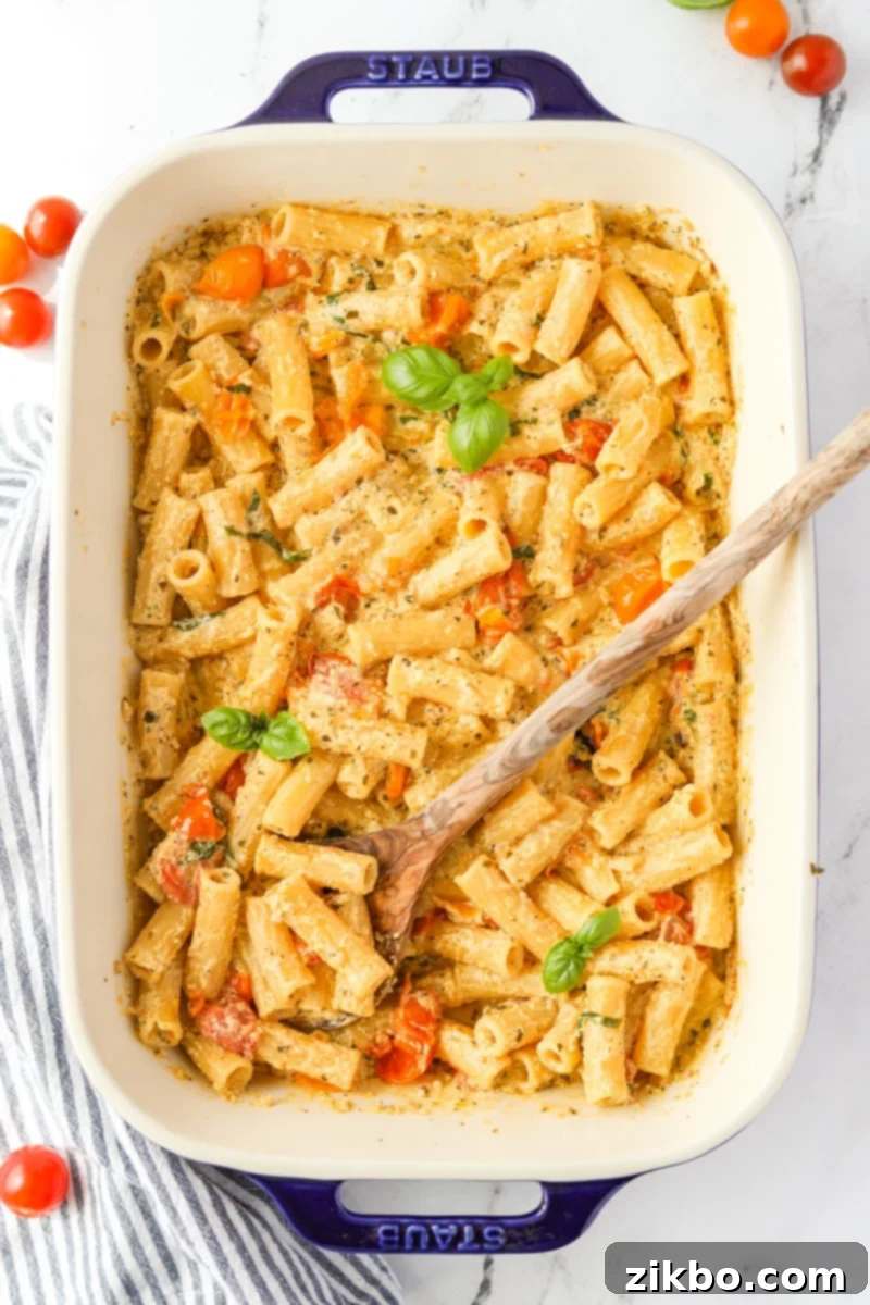 A large baking dish filled with the finished creamy Boursin pasta, topped with a generous sprinkle of fresh basil leaves, ready to be enjoyed.