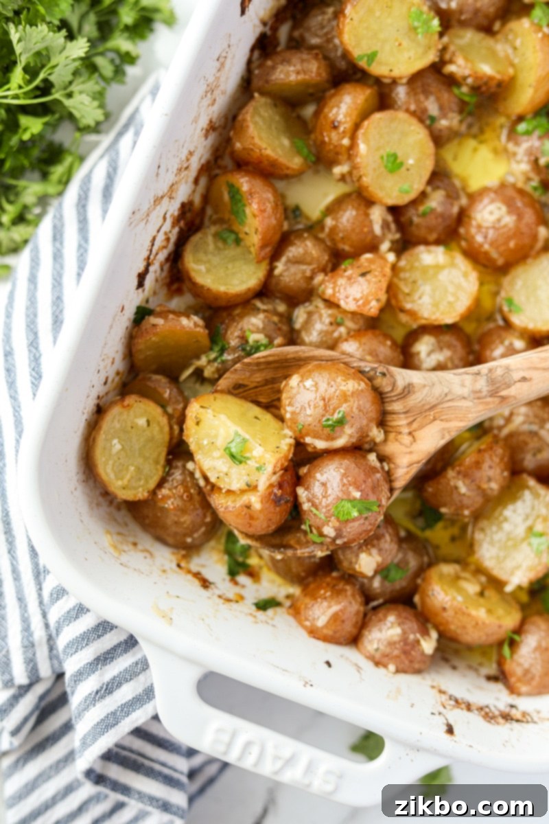 Scooping potatoes from a white baking dish.