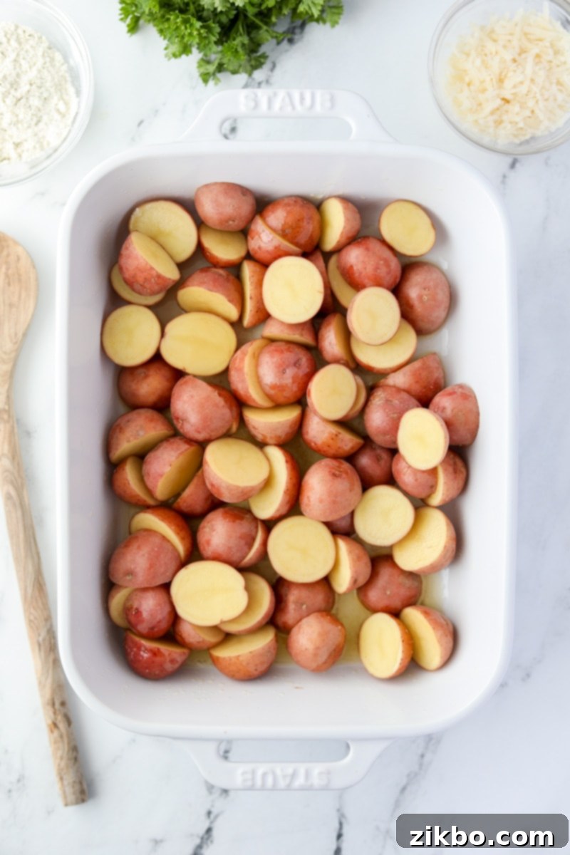 A white baking dish filled with halved baby potatoes.