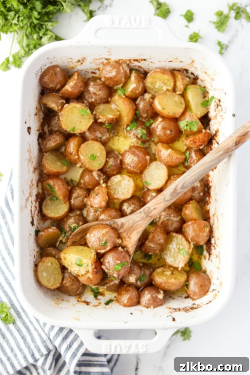 A spoon scooping potatoes from a baking dish.