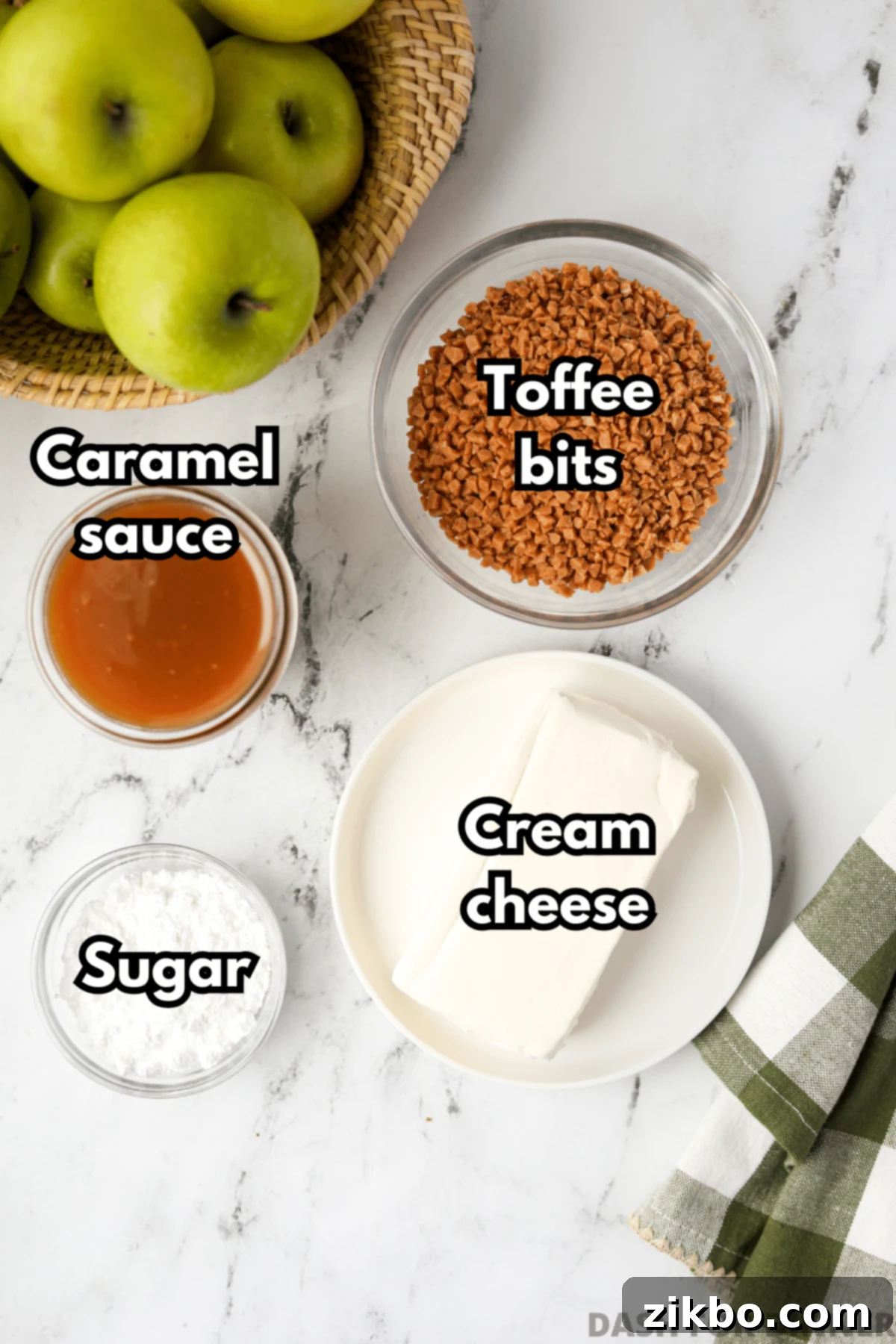 Creamy Caramel Apple Delight 3 A simple array of key ingredients laid out for making caramel apple dip: a block of cream cheese, powdered sugar, a bottle of caramel sauce, and a bowl of crunchy toffee bits.