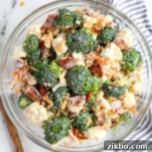 A bowl of broccoli salad garnished with cheese and bacon.