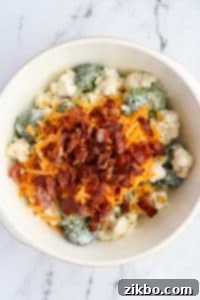 A bowl of broccoli salad with cheese and bacon on top.