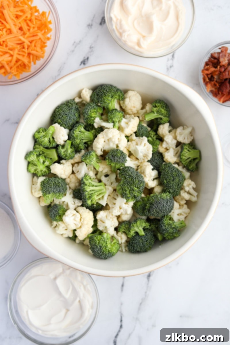 A large mixing bowl filled with freshly cut broccoli and cauliflower florets, ready for the dressing.