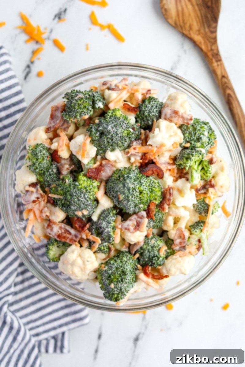 A large mixing bowl showcasing the completed creamy Amish broccoli and cauliflower salad, with all ingredients, including cheese and bacon, perfectly mixed and ready to serve.