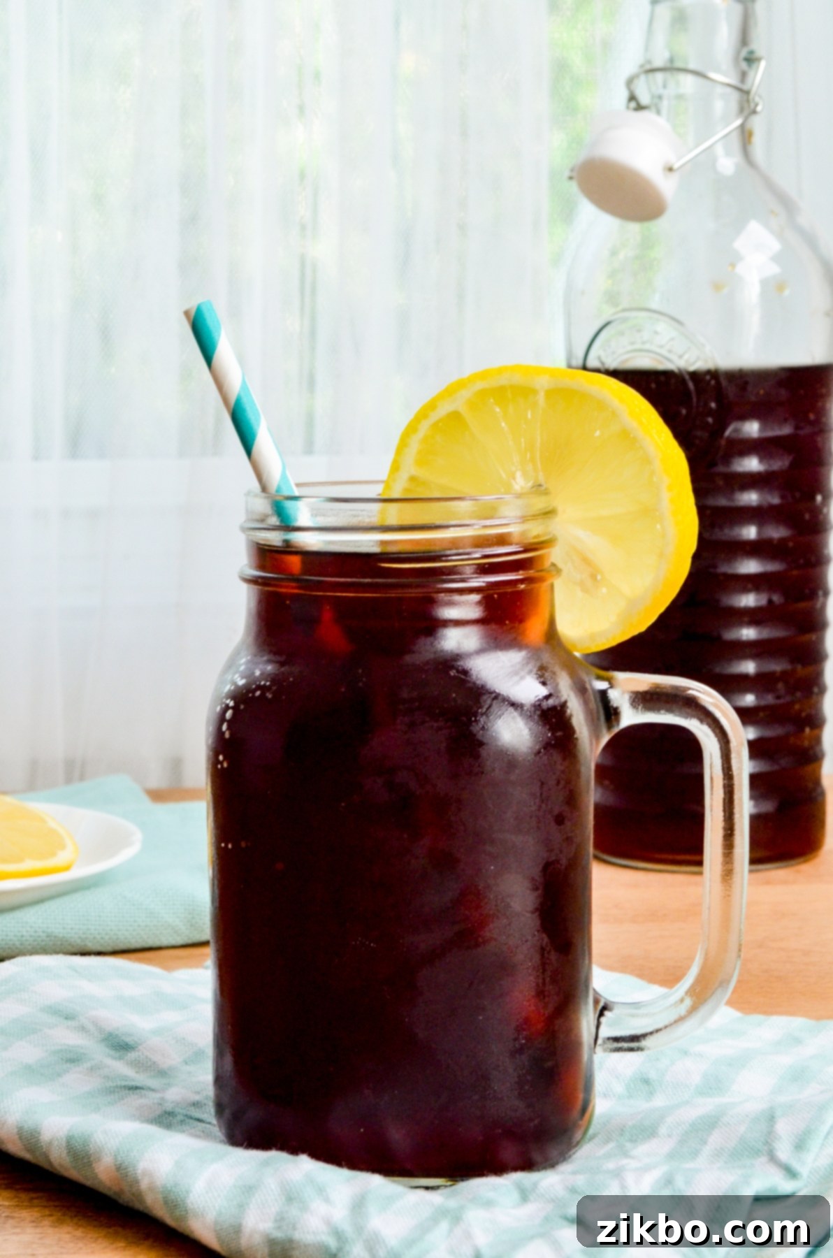 Instant Pot Iced Tea Crystal Clear and Smooth 2 A tall glass of Instant Pot Iced Tea garnished with a lemon slice, sitting on a wooden surface.