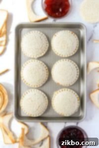 A baking sheet with round pressed sandwiches on it.