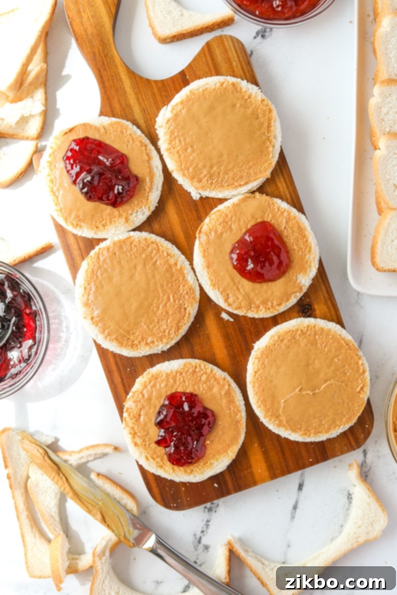 Adding jam and jelly on top of peanut butter coated bread pieces.