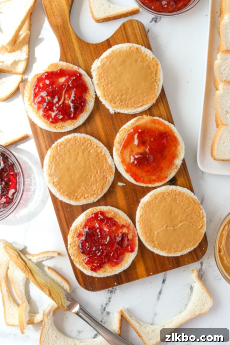 Spreading jam and jelly on top of peanut butter coated bread slices.