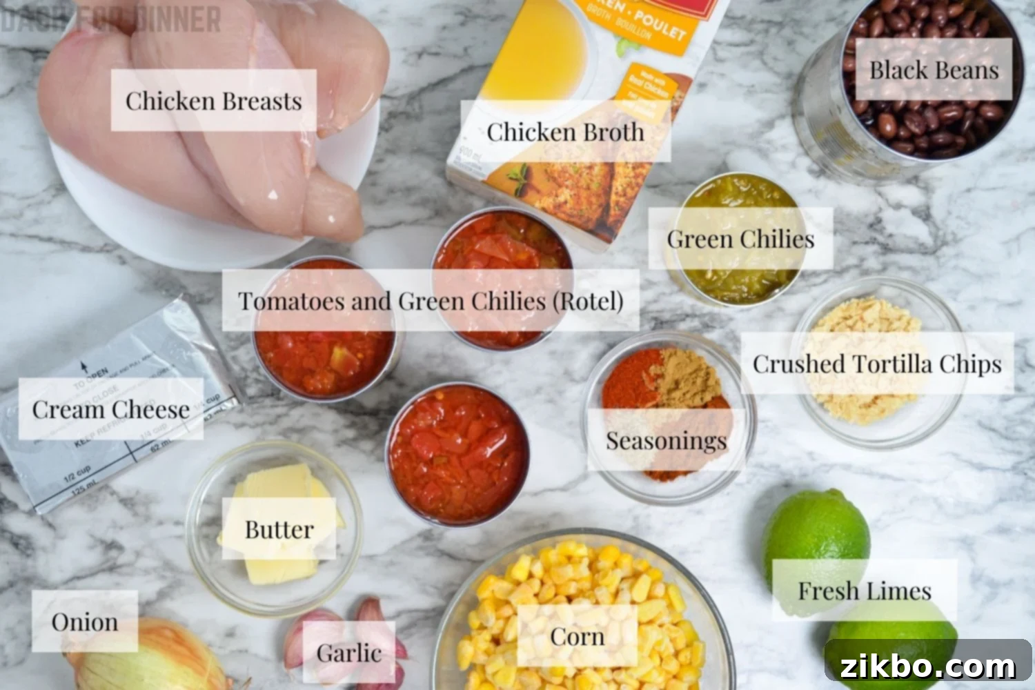 A flat lay photograph showcasing all the fresh and pantry ingredients needed to prepare Instant Pot Creamy Chicken Tortilla Soup, including chicken breasts, cans of beans and tomatoes, corn, and spices.