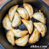 An air fryer basket, with cooked frozen pierogies, perfectly golden and crispy.