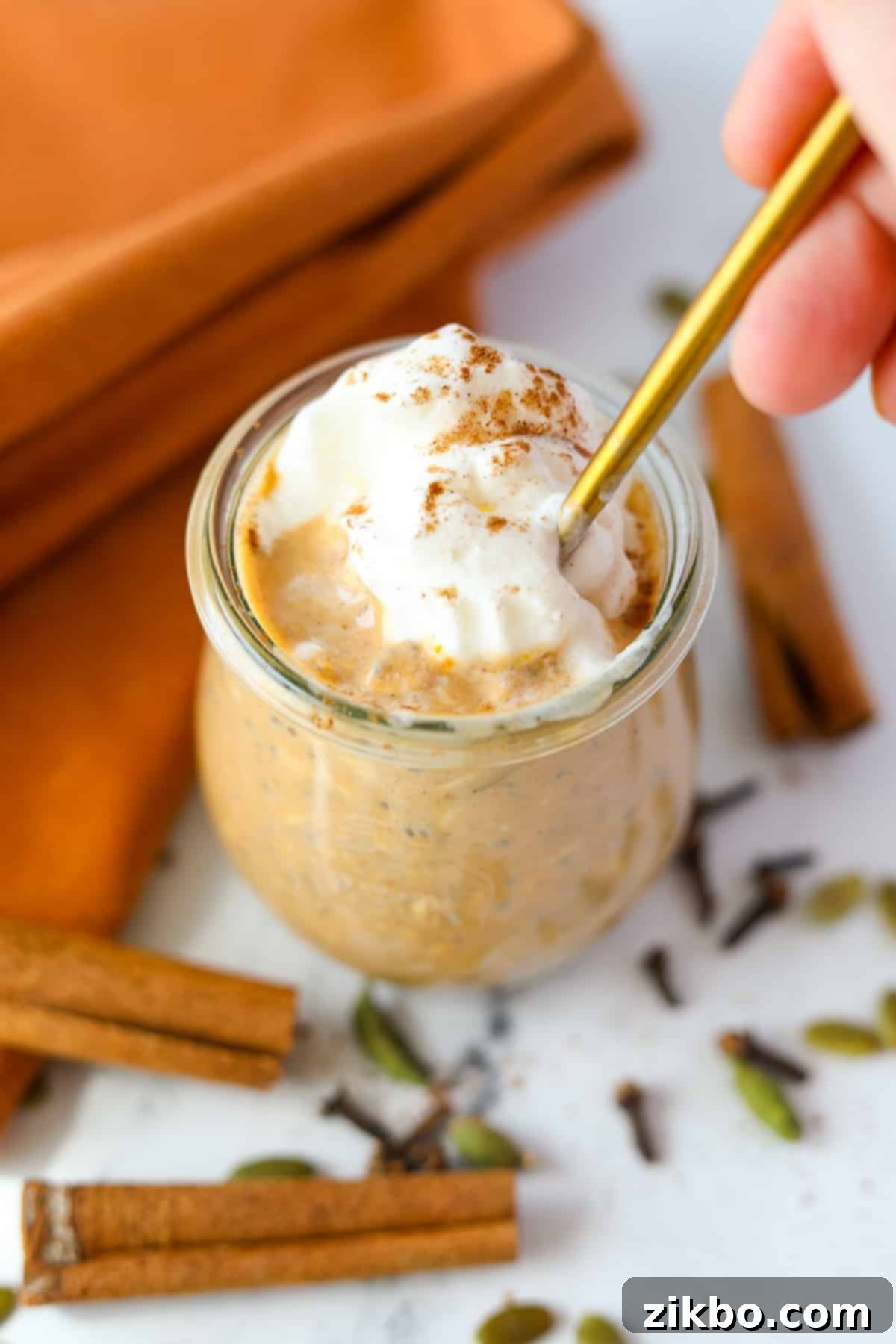 A spoon taking a portion from a jar of pumpkin overnight oatmeal.