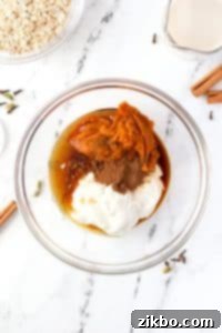 A bowl filled with greek yogurt, pumpkin, maple syrup, and spices.