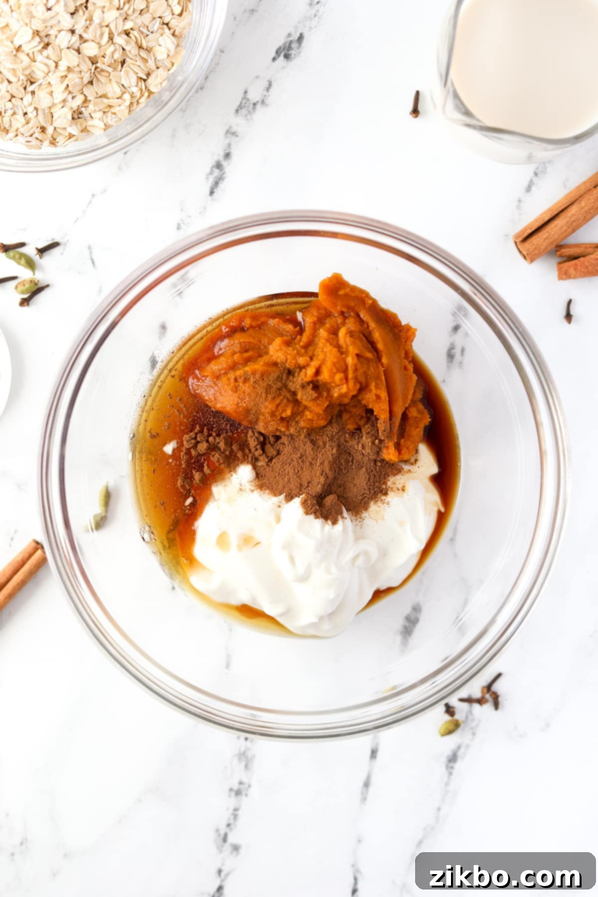 A bowl filled with greek yogurt, pumpkin, maple syrup, and spices.