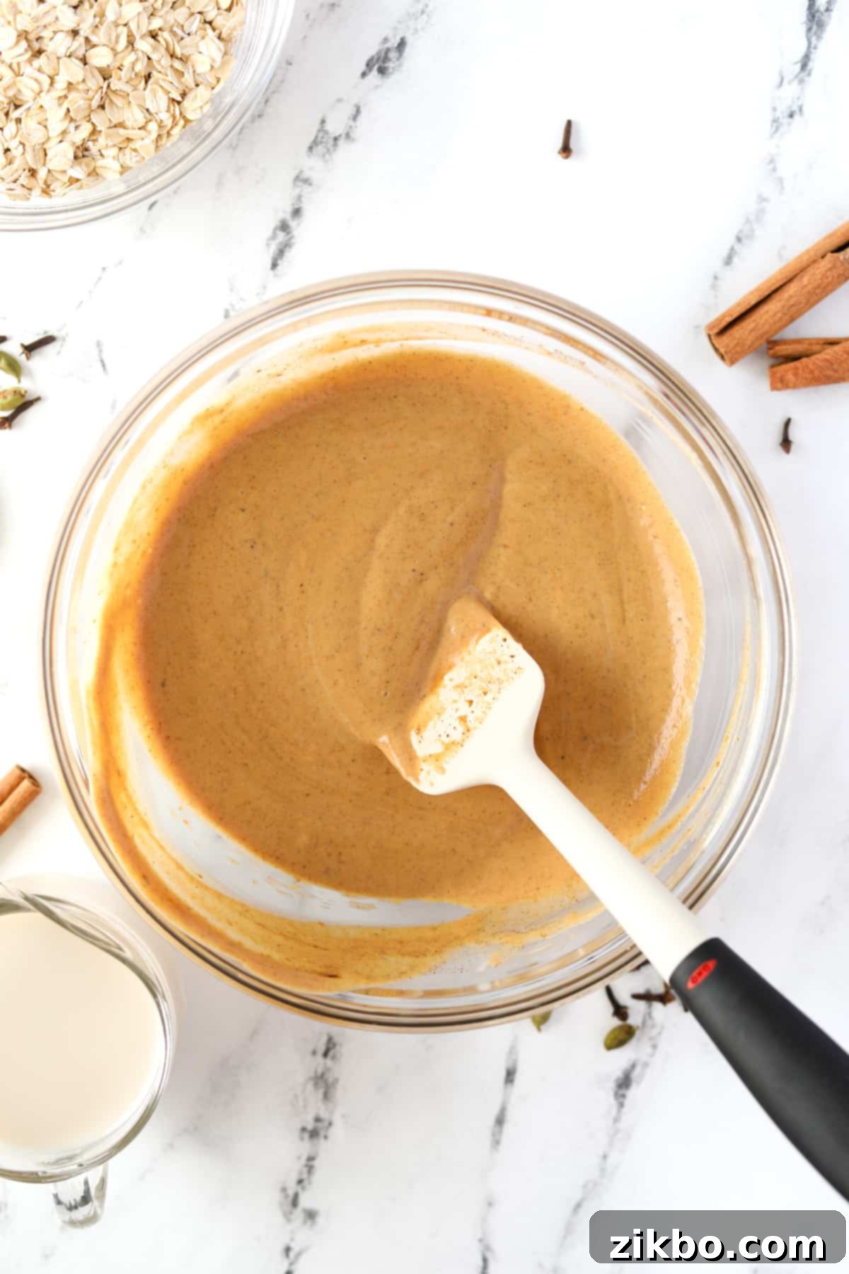 A silicone spatula stirring a pumpkin colored liquid.