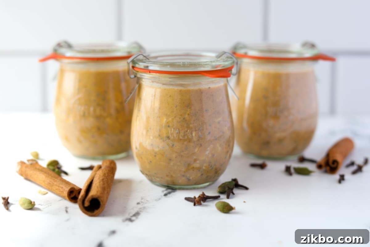 Three jars filled with pumpkin overnight oatmeal, resting on a countertop.