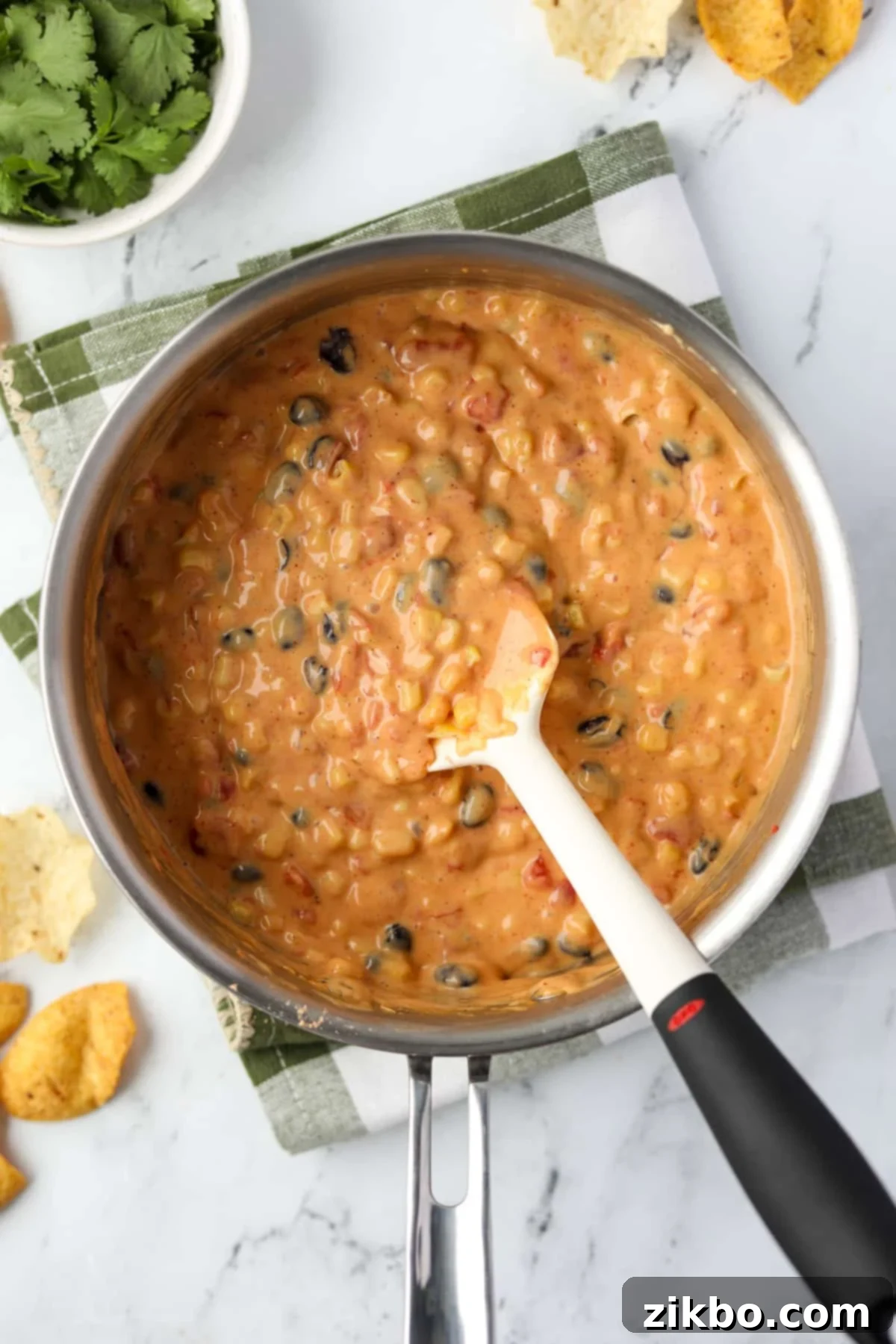 Zesty Southwest Delight 9 Stirring together Velveeta, Rotel, corn, and black beans to combine all ingredients thoroughly.