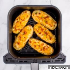 Perfectly Crispy Air Fryer Twice Baked Potatoes 16 An air fryer basket filled with loaded twice-baked potato halves, golden and bubbly, ready to be served.