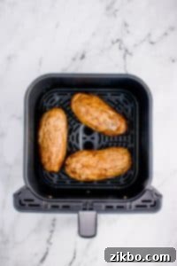 Baked potatoes in an air fryer basket.