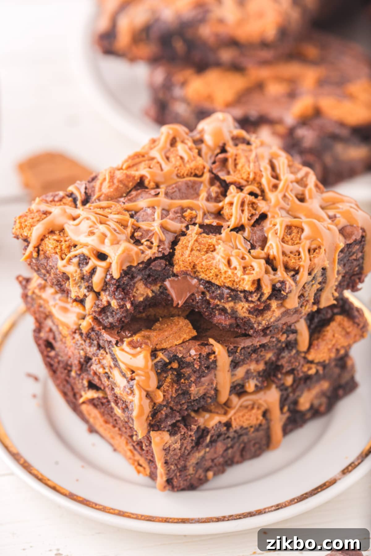 A delectable stack of three fudgy Biscoff brownies, topped with a generous layer of creamy cookie butter and garnished with crushed Biscoff cookies.