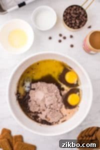 A bowl filed with brownie mix, eggs, milk, and melted butter.