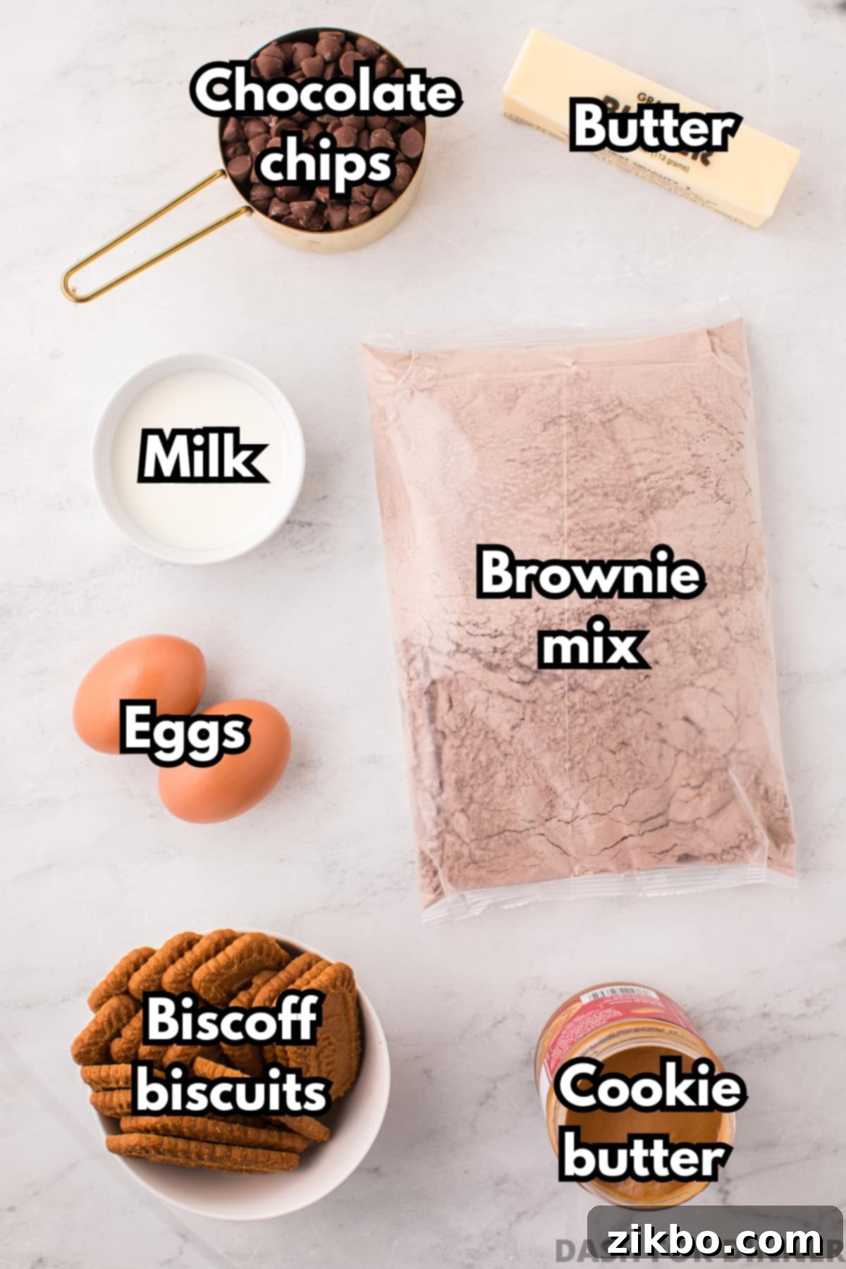 A collection of ingredients neatly arranged for making Biscoff brownies, including brownie mix, eggs, butter, milk, chocolate chips, Biscoff spread, and Biscoff cookies.