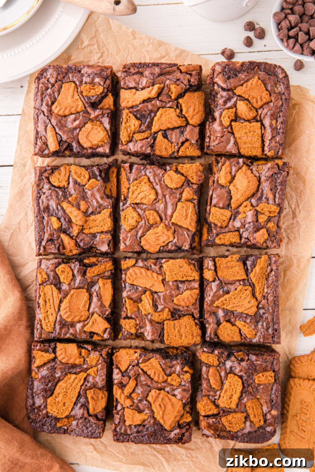 A full pan of baked Biscoff brownies, neatly sliced into twelve squares and topped with crushed Lotus Biscoff cookies, ready to be served.
