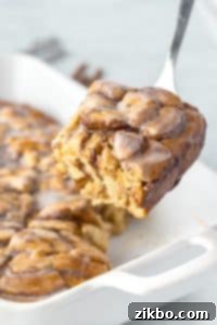 Lifting a portion of cinnamon roll breakfast bake from a baking dish.