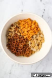 A large bowl containing pretzels, goldfish crackers, nuts, and cereal.
