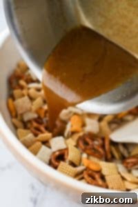 Pouring butter and seasonings over a dry snack mix in a large bowl.