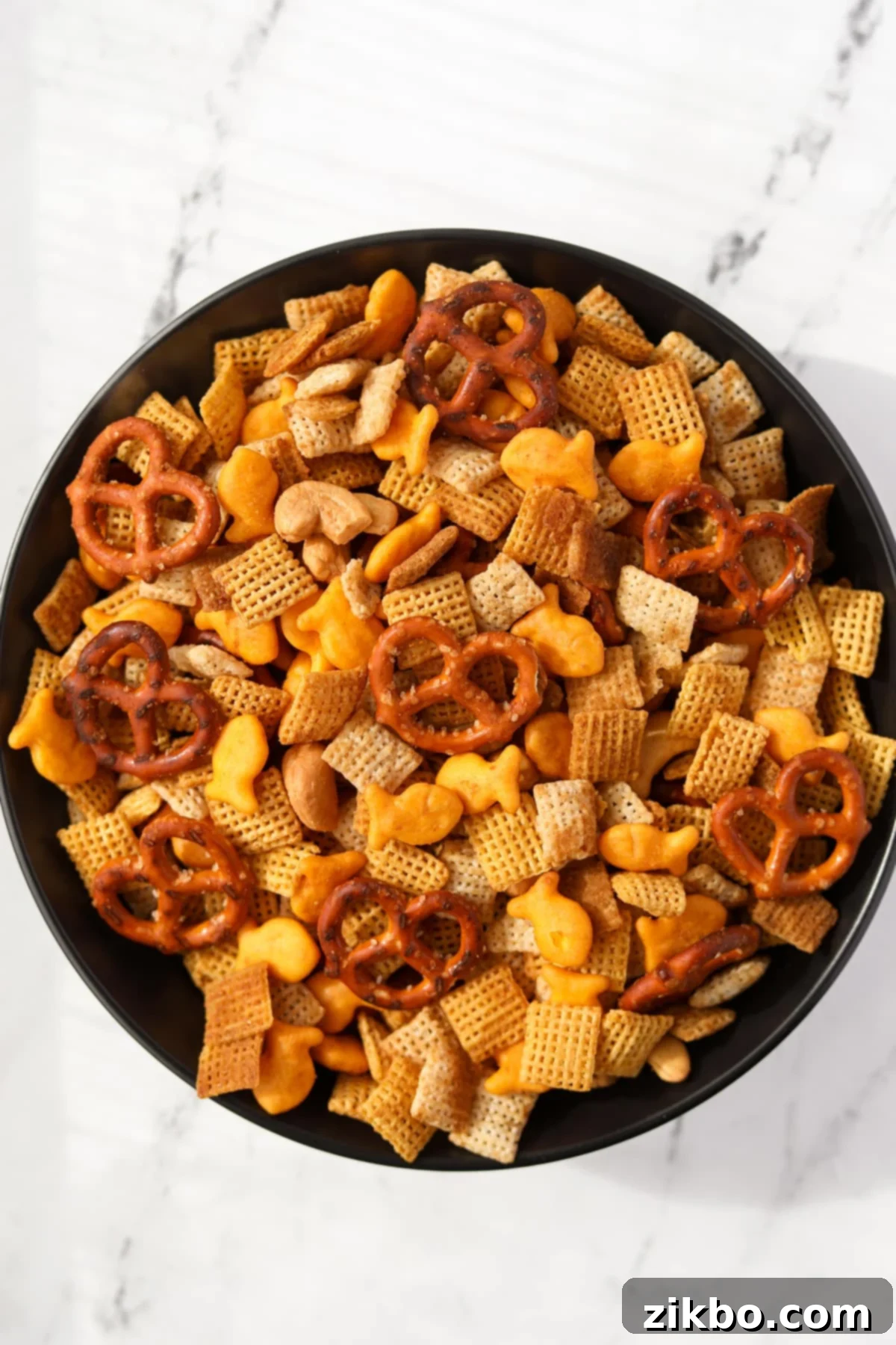 A bowl of homemade snack mix with pretzels, crackers, cereal, and nuts.