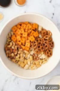 A bowl with cheese crackers, Chex mix, pretzels, and mixed nuts.