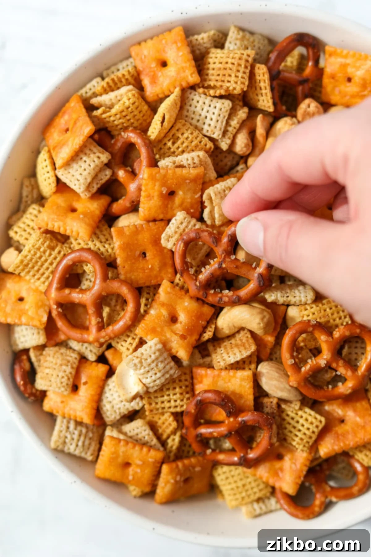 Taking a pretzel from a bowl of snack mix.