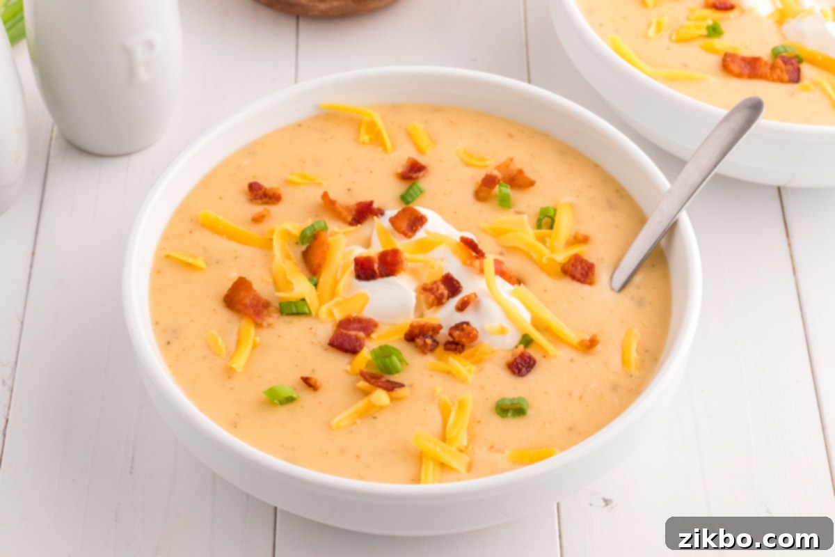 A rustic shot of a bowl of baked potato soup on a white shiplap table, highlighting its comforting appeal.