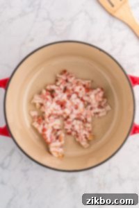 Raw diced bacon sizzling in a Dutch oven.