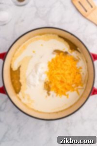 Cream, cheese, and sour cream added to soup in a Dutch oven.