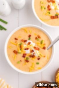 Bowl of loaded baked potato soup with garnishes.