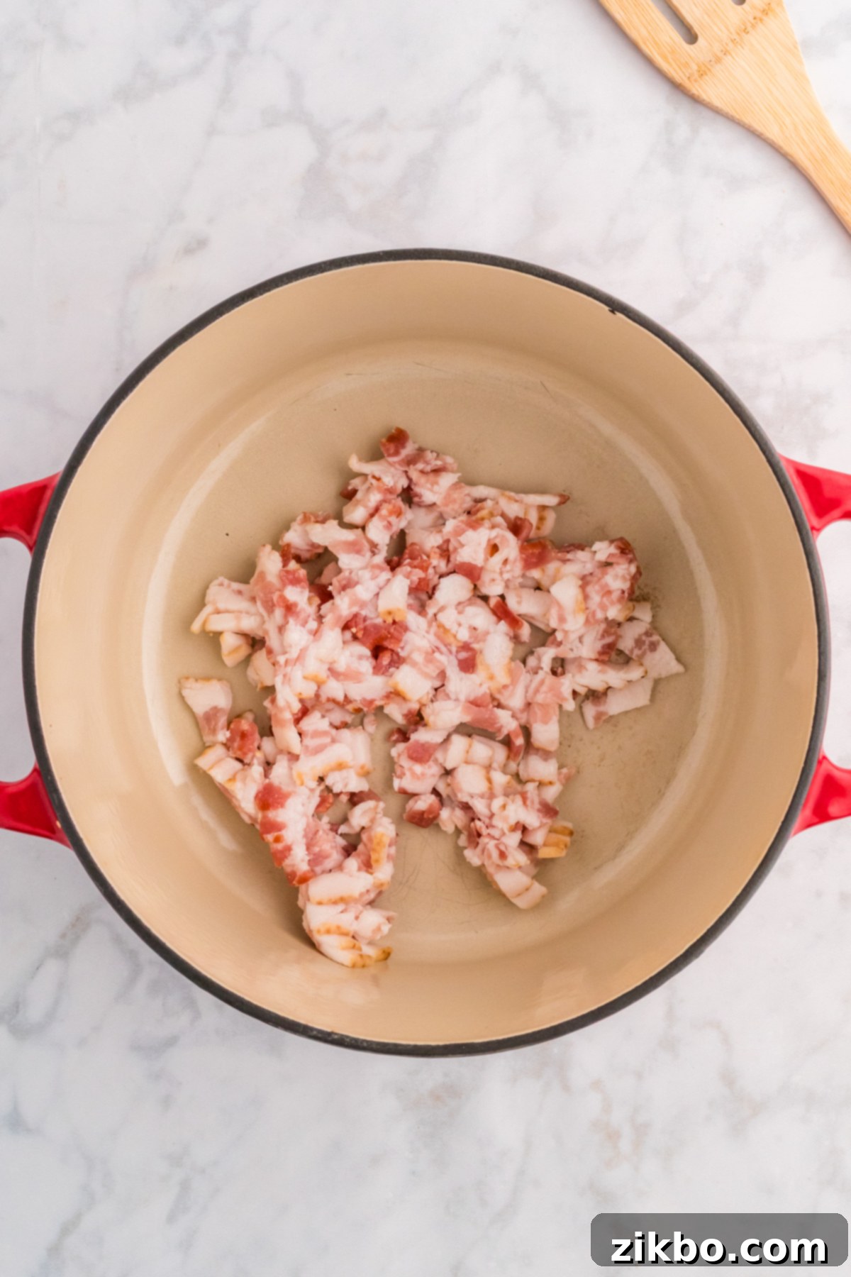 Diced raw bacon sizzling in a large Dutch oven, preparing to become crispy for the soup.